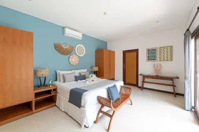 a bedroom with a large bed and a chair at Villa Coco Bali in Seminyak