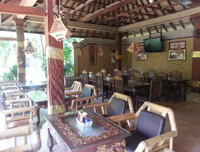a dining room with tables and chairs and a table and a room with a dining at Dewa Bharata Bungalows Legian in Legian