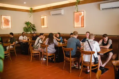 a group of people sitting at tables in a restaurant at Rama Residence Seminyak in Seminyak