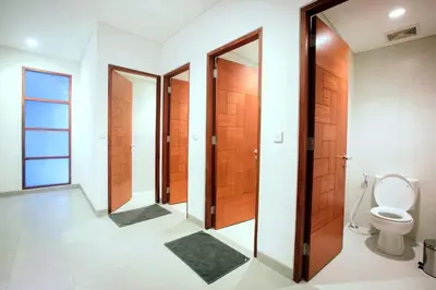 a bathroom with wooden doors and a toilet at Pudak Sari Unizou Hostel in Kuta