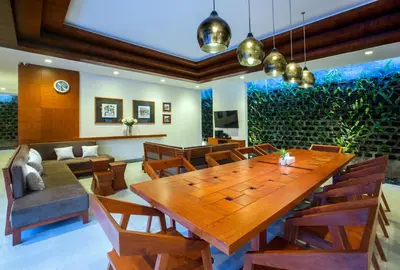 a dining room with a wooden table and chairs at Pudak Sari Unizou Hostel in Kuta