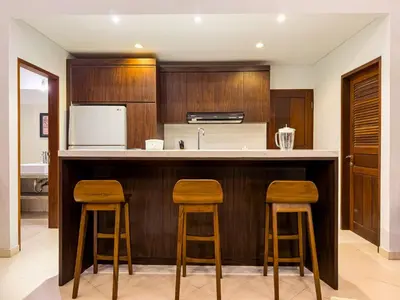 a kitchen with wooden cabinets and a counter with stools at Villa Bugis Seminyak in Seminyak