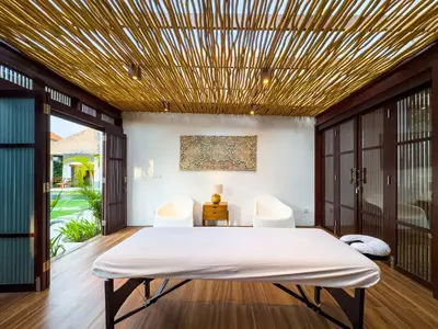 a bedroom with a bed and two chairs at Villa Bugis Seminyak in Seminyak