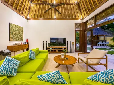 a living room with green furniture and a ceiling fan at Villa Bugis Seminyak in Seminyak