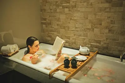 a man sitting in a bath tub reading a book at Lasanti Villas Seminyak in Seminyak