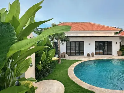 a villa with a swimming pool in front of a house at Amerta Villa Seminyak in Seminyak