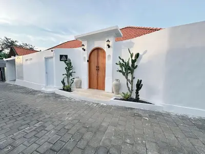 a white house with a wooden door on a street at Amerta Villa Seminyak in Seminyak