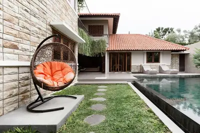 a chair sitting in the grass next to a pool at Dasa Villa in Seminyak