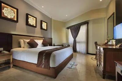 a bedroom with a large bed and a flat screen tv at Pelangi Bali Hotel & Spa in Seminyak