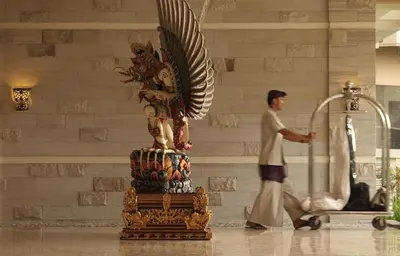 a man walking past a statue in a building at The Seminyak Beach Resort & Spa in Seminyak