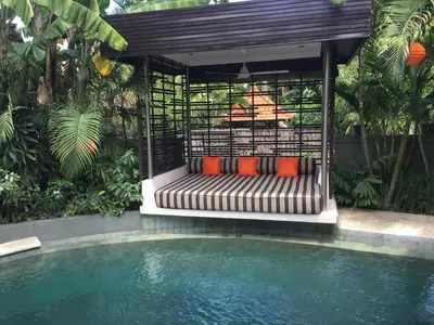 a bench next to a swimming pool next to a house at Esha Villa Umalas 2 in Kerobokan