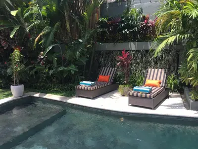 two chairs sitting next to a swimming pool at Esha Villa Umalas 2 in Kerobokan