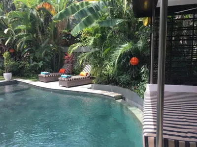 a swimming pool in a garden with palm trees at Esha Villa Umalas 2 in Kerobokan