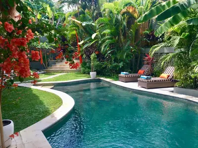 a swimming pool in a garden with palm trees at Esha Villa Umalas 2 in Kerobokan