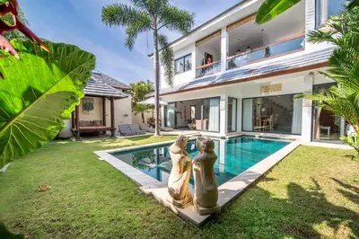 a villa with a pool and two statues next to it at Villa Wiana by Villa Finder in Seminyak