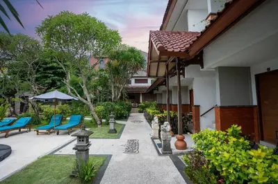 a courtyard of a house with blue chairs and trees at Hotel Sinar Bali Legian in Legian