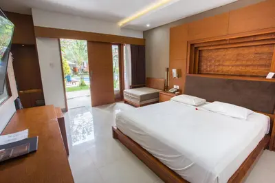 a bedroom with a large white bed and a desk at Hotel Sinar Bali Legian in Legian