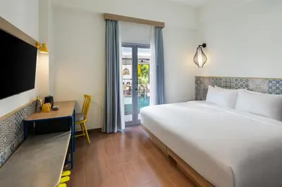a bedroom with a bed and a desk and a tv at Kampi Hotel Legian in Legian