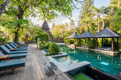 a pool at a resort with blue chairs and trees at Bali Garden Beach Resort in Kuta