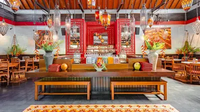 a restaurant with tables and chairs and a bar at Bali Garden Beach Resort in Kuta
