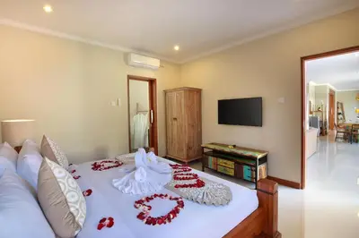 a bedroom with a bed with red flowers on it at Kae Villa Anggrek in Seminyak