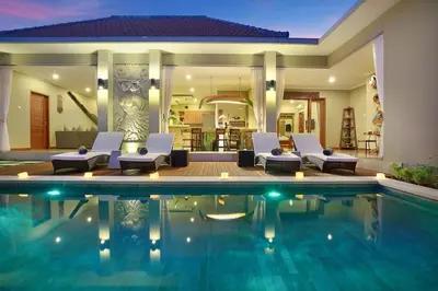 a villa with a swimming pool at night at Kae Villa Anggrek in Seminyak
