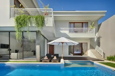 a villa with a swimming pool and an umbrella at Daha Mansions Seminyak in Seminyak
