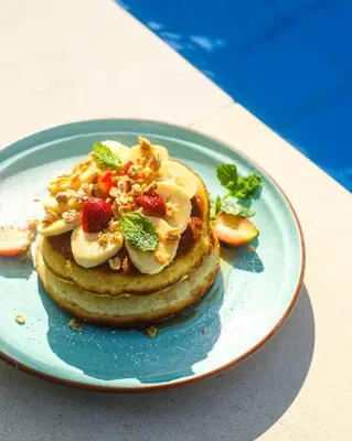 a plate with a stack of pancakes with fruit and nuts at Daha Mansions Seminyak in Seminyak