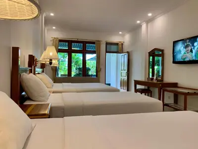 a bedroom with three beds and a flat screen tv at Febri's Hotel & Spa in Kuta