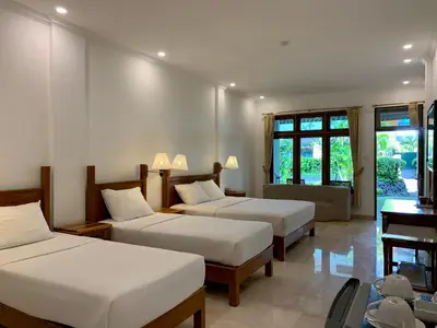 a room with three beds and a desk and windows at Febri's Hotel & Spa in Kuta