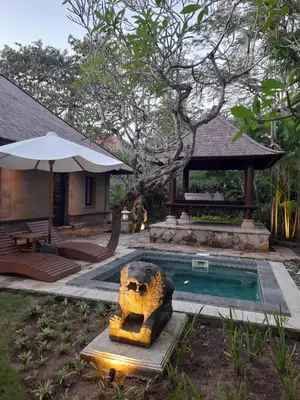 a swimming pool with a statue next to a house at The Royal Beach Seminyak Bali in Seminyak