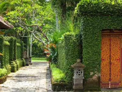 a garden with a walkway next to a building at The Royal Beach Seminyak Bali in Seminyak