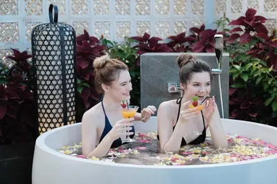 two women sitting in a bath tub with drinks at The Vira Bali Boutique Hotel & Suite in Kuta