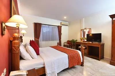 a hotel room with a bed and a television at Puri Dewa Bharata Hotel & Villas in Legian