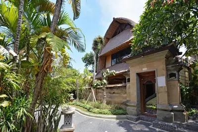 a building with palm trees in front of it at Puri Dewa Bharata Hotel & Villas in Legian