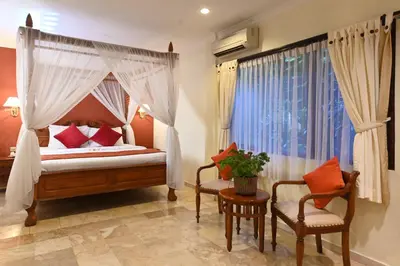 a bedroom with a canopy bed and two chairs at Puri Dewa Bharata Hotel & Villas in Legian
