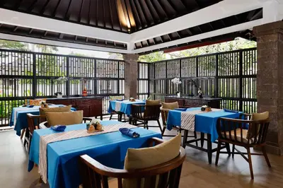 a restaurant with blue tables and chairs and windows at Rama Beach Resort and Villas in Kuta
