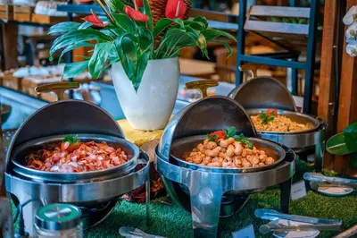 a buffet of food in metal pots on a table at Rama Garden Hotel Bali in Legian
