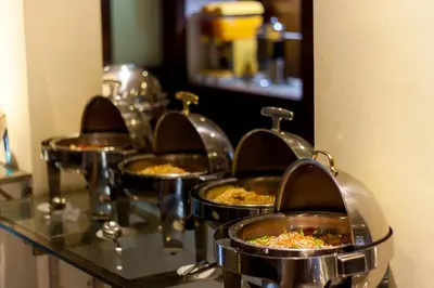 a row of trays filled with food on a counter at Champlung Mas Hotel Legian in Legian