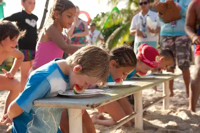 a group of children eating food at a picnic table at Hard Rock Hotel Bali in Kuta