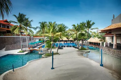 a pool at a resort with palm trees and water at Hard Rock Hotel Bali in Kuta