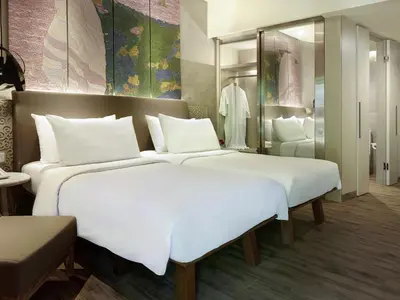 a large bedroom with two beds and a mirror at Mercure Kuta Bali in Kuta