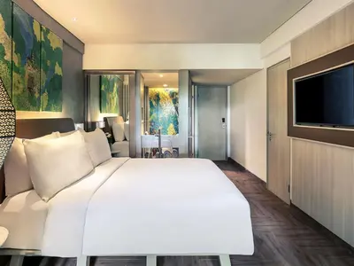 a bedroom with a large white bed and a flat screen tv at Mercure Kuta Bali in Kuta