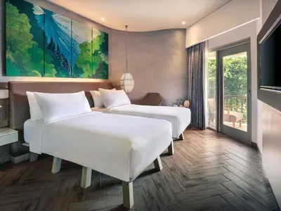 two beds in a hotel room with a painting on the wall at Mercure Kuta Bali in Kuta