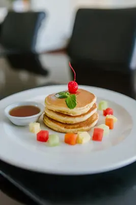 a plate with a stack of pancakes and a cherry on top at C151 Smart Villas at Seminyak in Seminyak