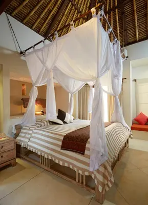 a bedroom with a bed with a mosquito net at Visakha Sanur by Puri Signatures in Sanur