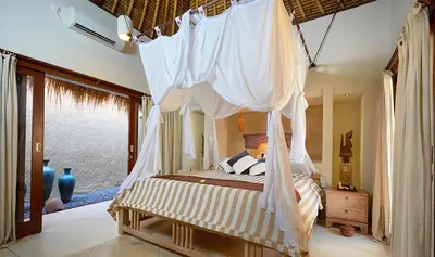 a bedroom with a canopy bed with mosquito nets at Visakha Sanur by Puri Signatures in Sanur