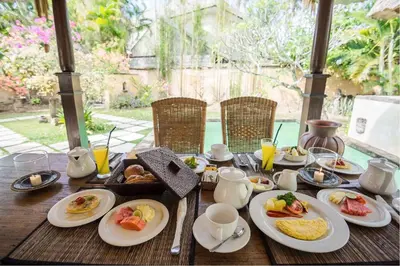 a wooden table with plates of breakfast food on it at Visakha Sanur by Puri Signatures in Sanur