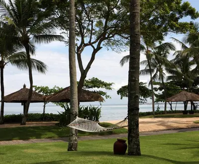 a hammock between palm trees on the beach at InterContinental Bali Resort by IHG in Jimbaran