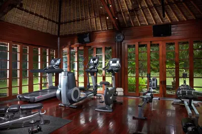 a gym with several treadmills and exercise bikes at The Oberoi Beach Resort, Bali in Seminyak